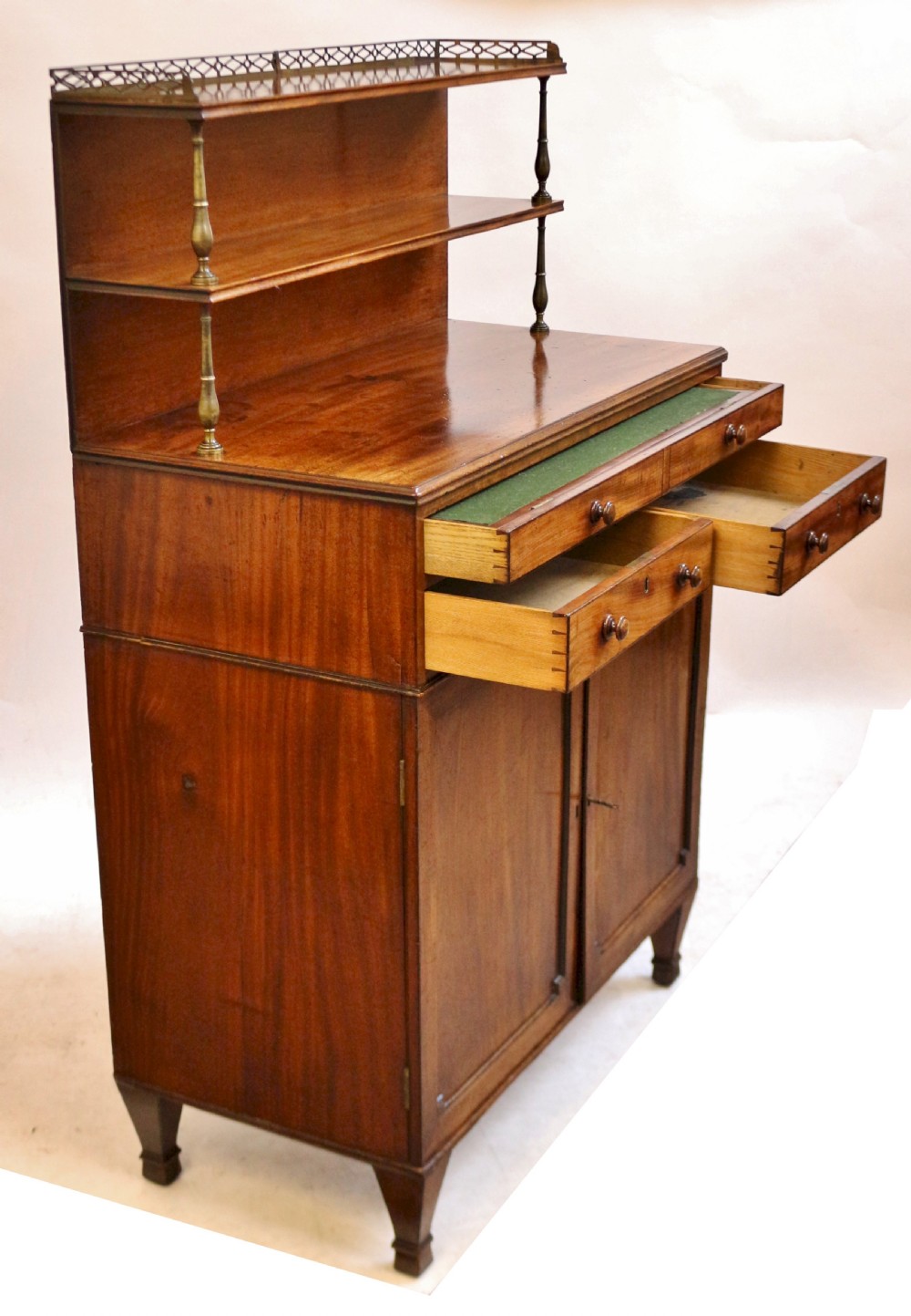 A Regency mahogany chiffonier with a two-tier brass-galleried shelf unit above a fitted writing drawer and two-door cabinet base. View VII