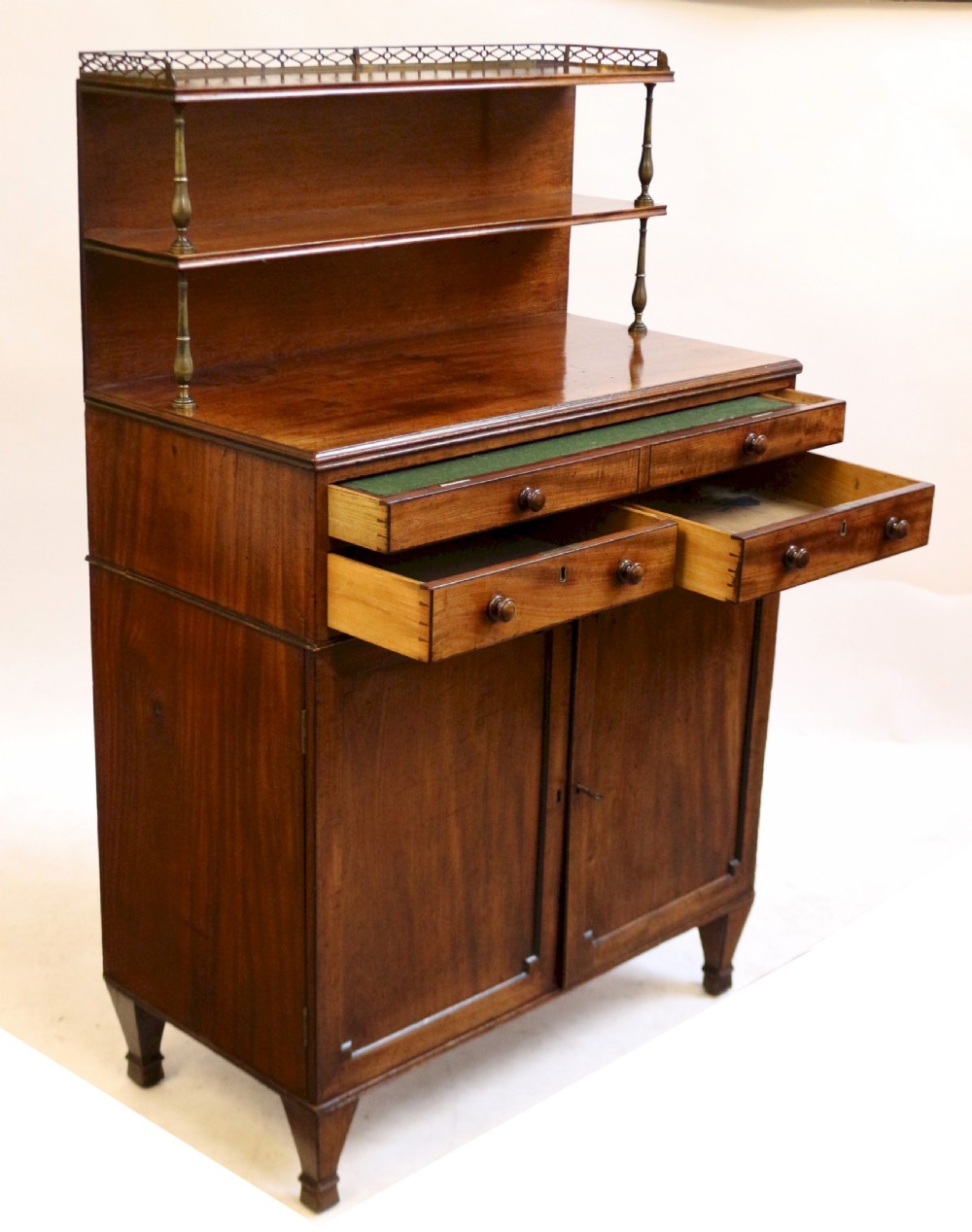 A Regency mahogany chiffonier with a two-tier brass-galleried shelf unit above a fitted writing drawer and two-door cabinet base. View VIII