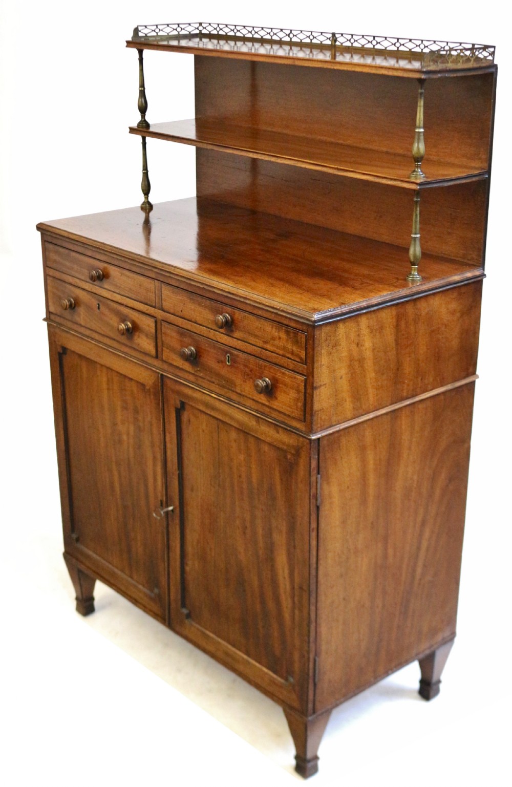 A Regency mahogany chiffonier with a two-tier brass-galleried shelf unit above a fitted writing drawer and two-door cabinet base. View IX