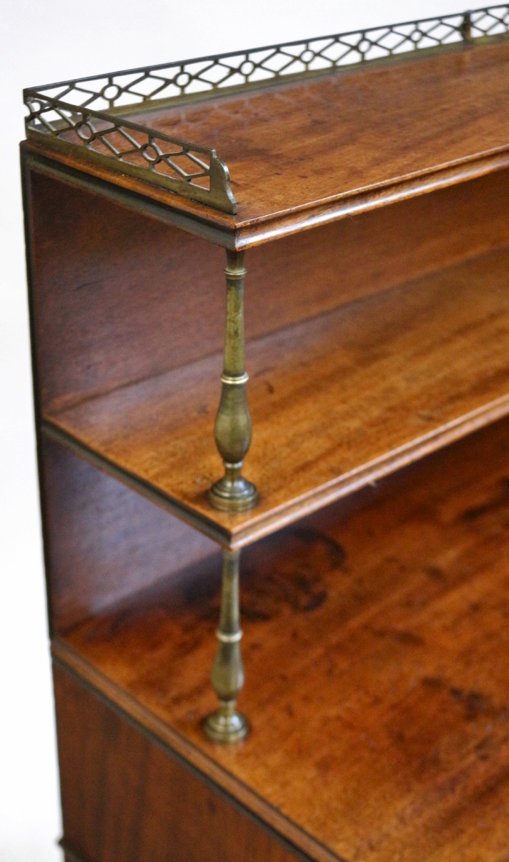 A Regency mahogany chiffonier with a two-tier brass-galleried shelf unit above a fitted writing drawer and two-door cabinet base. View XV