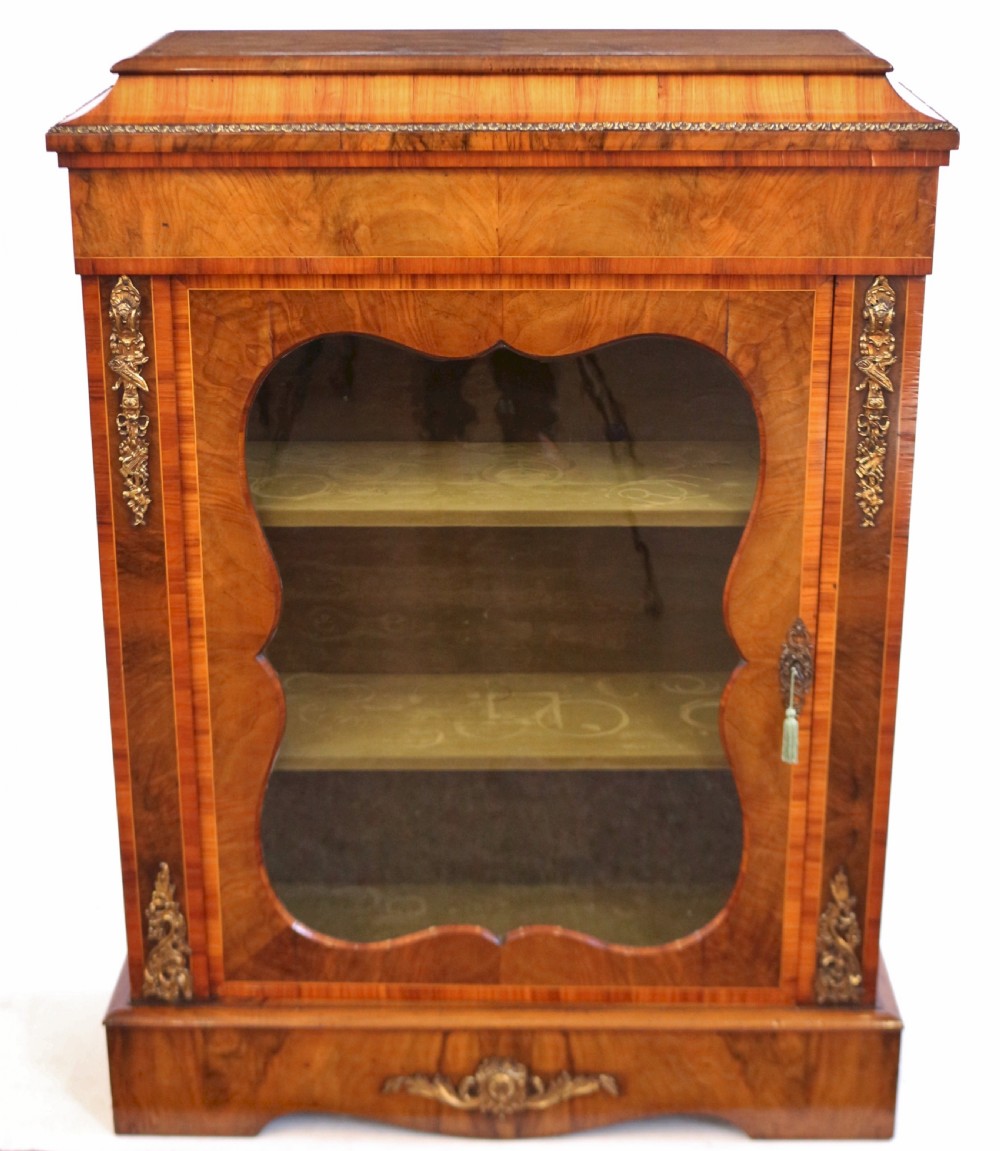 A Victorian walnut and kingwood pier cabinet with a single glazed door, brass mounts, and internal display shelves.