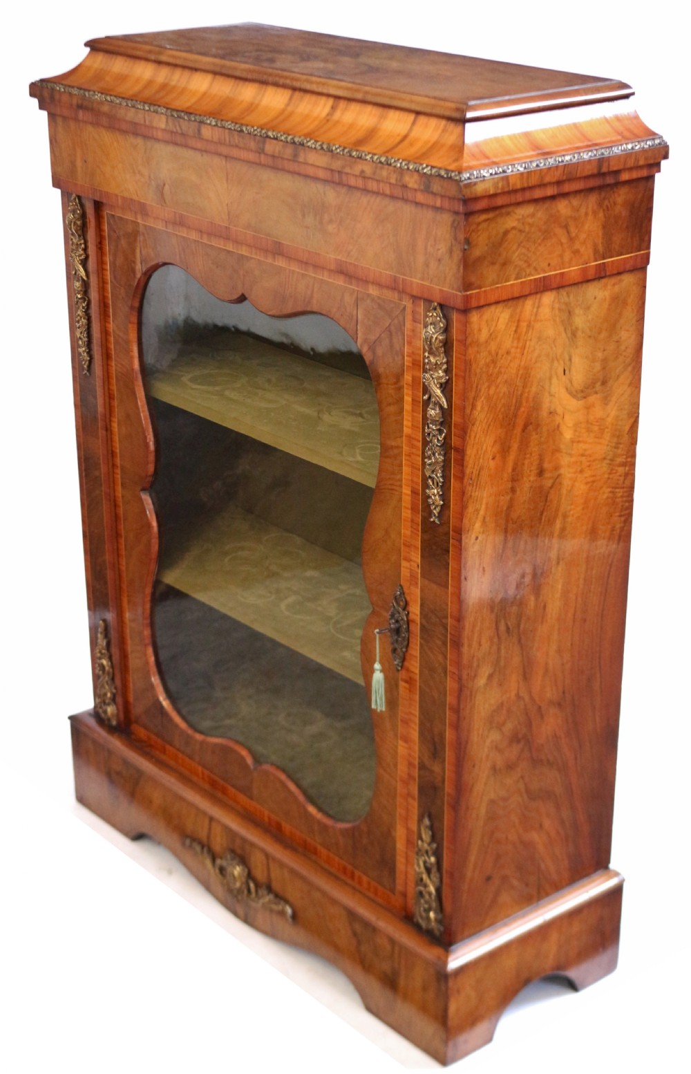 A Victorian walnut and kingwood pier cabinet with a single glazed door, brass mounts, and internal display shelves. View IV