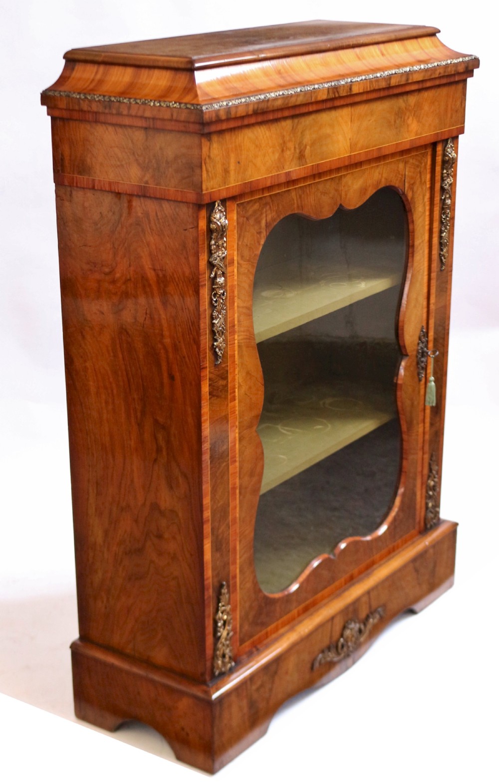 A Victorian walnut and kingwood pier cabinet with a single glazed door, brass mounts, and internal display shelves. View V