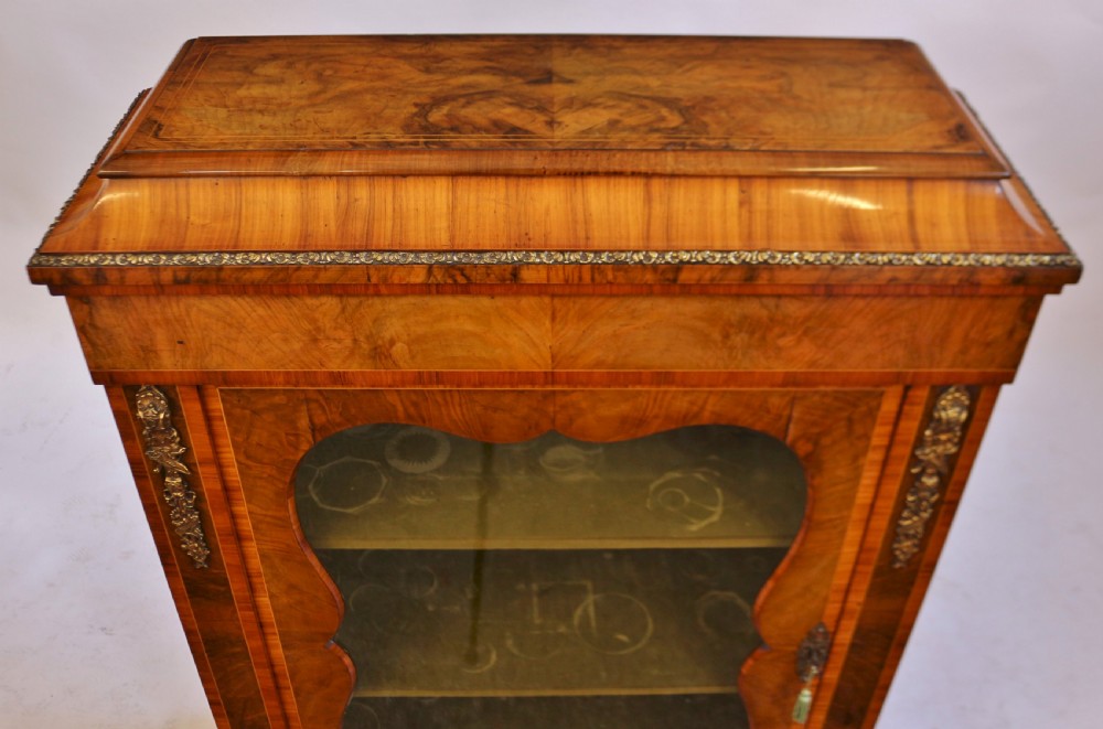 A Victorian walnut and kingwood pier cabinet with a single glazed door, brass mounts, and internal display shelves. View VII