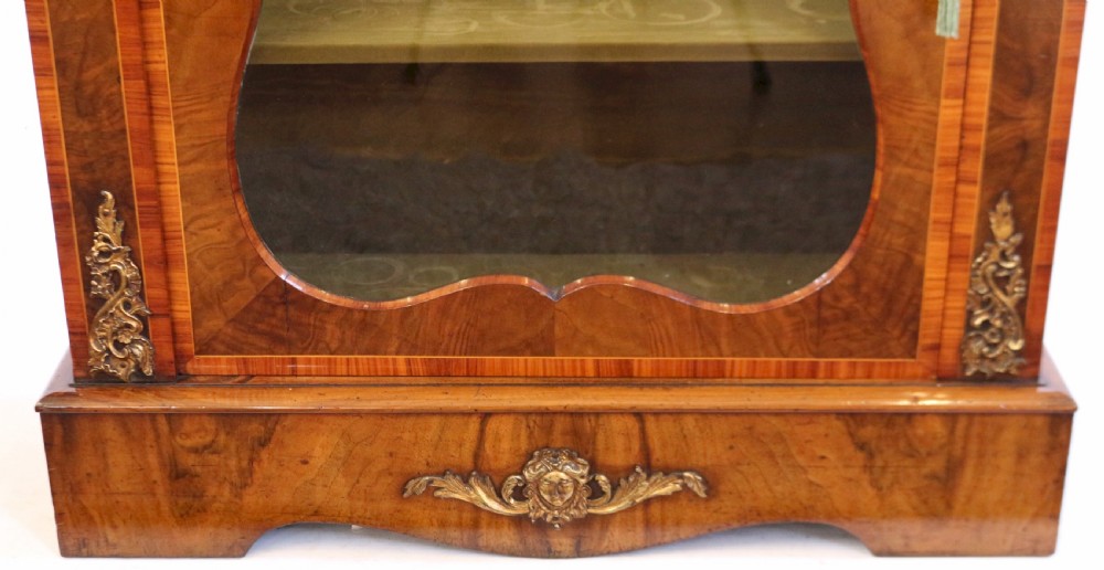 A Victorian walnut and kingwood pier cabinet with a single glazed door, brass mounts, and internal display shelves. View VIII