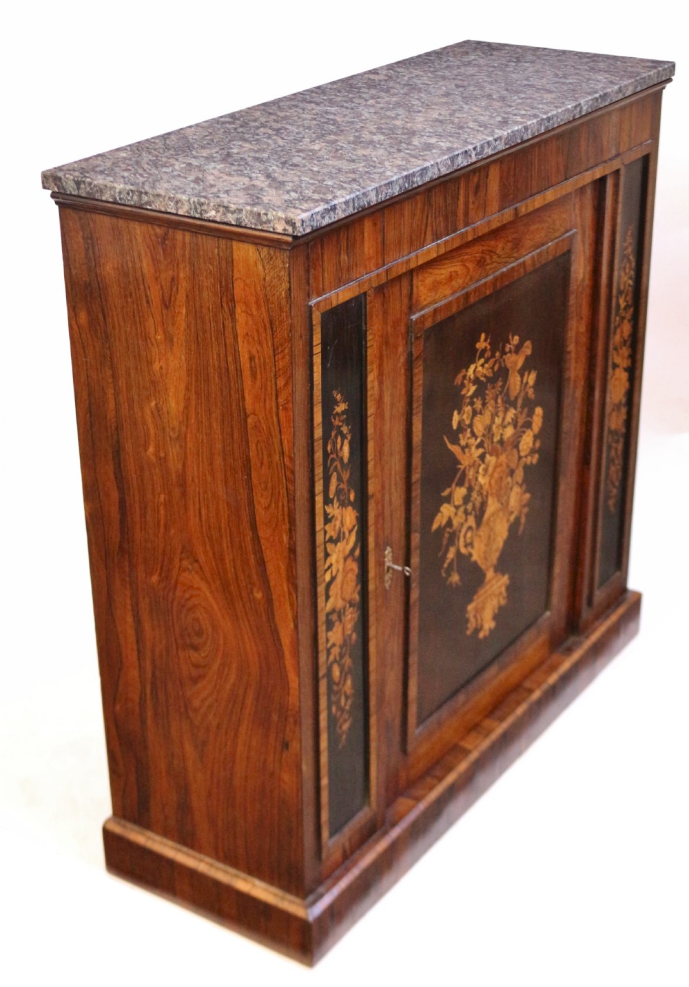 A Victorian rosewood side cupboard featuring an inlaid floral marquetry central door, flanking inlaid side panels, and a grey marble top. View IV