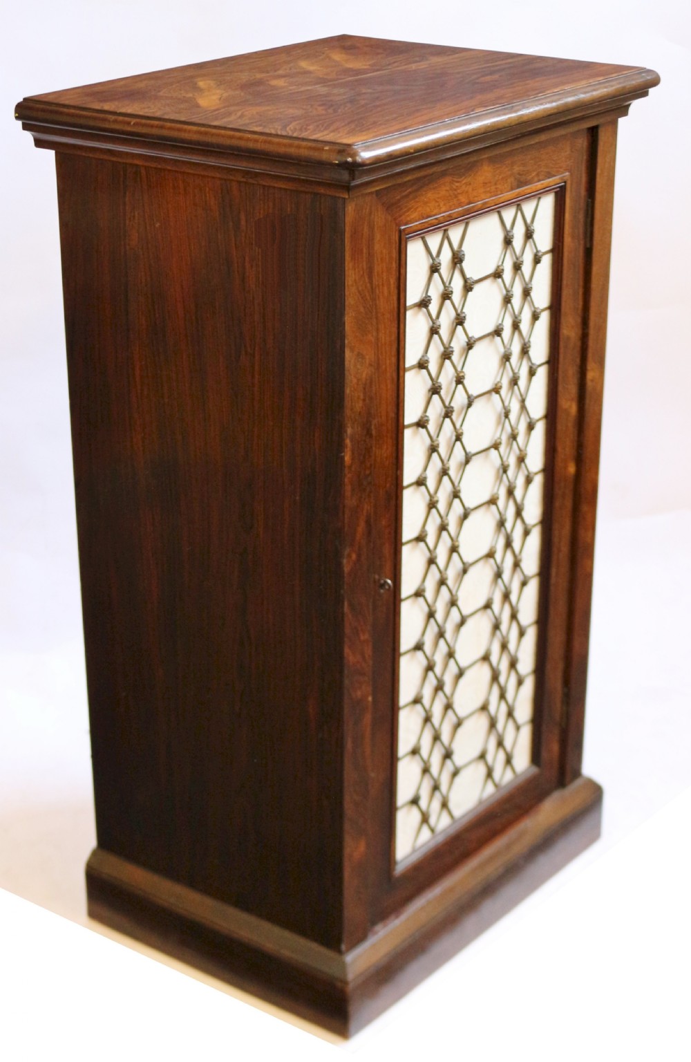 An antique William IV rosewood cupboard featuring a single door inset with a decorative brass lattice grille over a cream fabric backing. View III