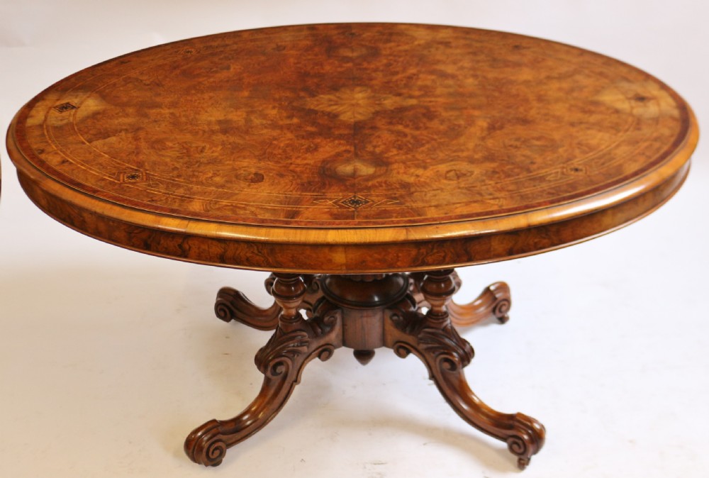 An antique Victorian oval tilt-top loo table crafted from figured walnut with marquetry inlay and carved pedestal legs. View III