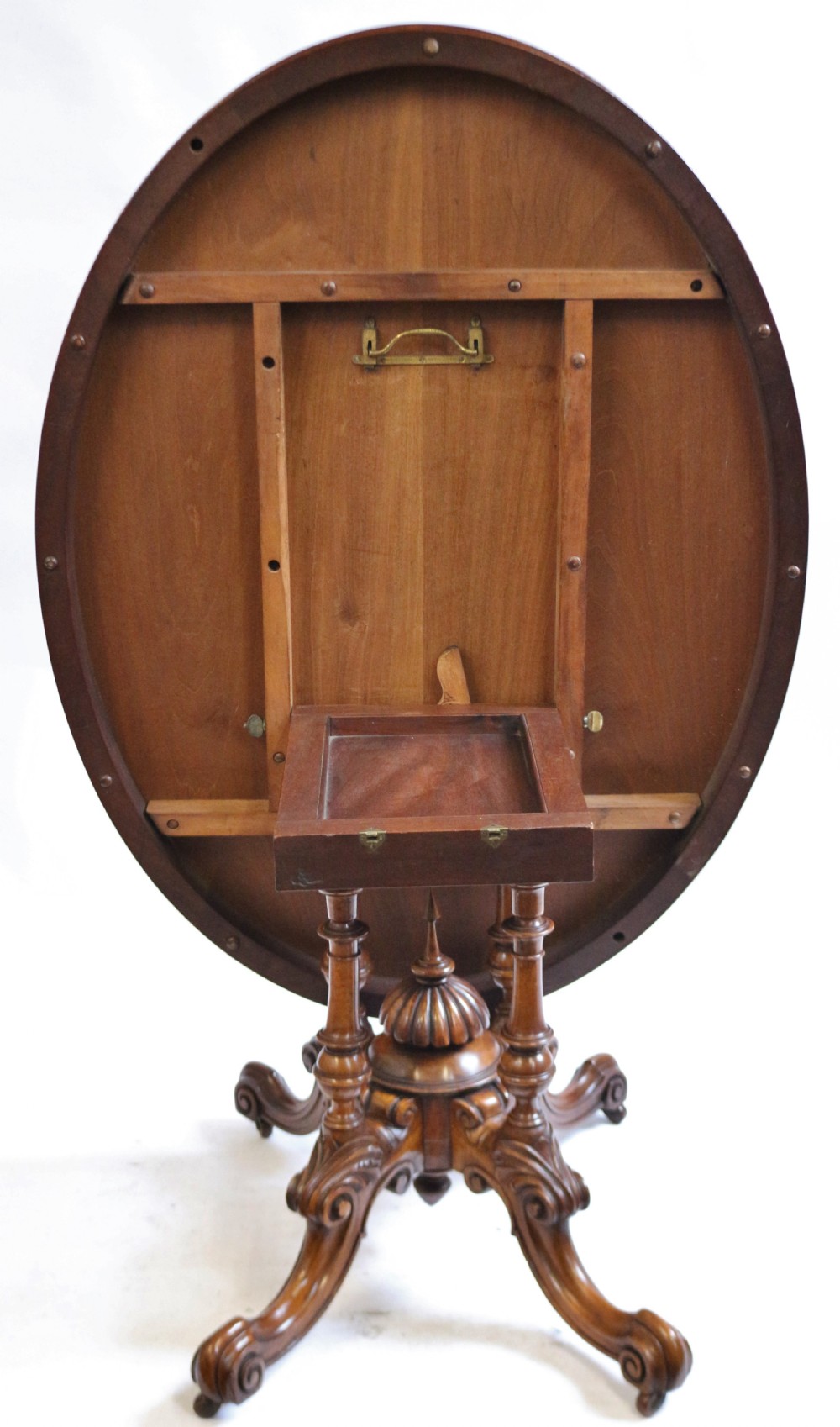 An antique Victorian oval tilt-top loo table crafted from figured walnut with marquetry inlay and carved pedestal legs. View V