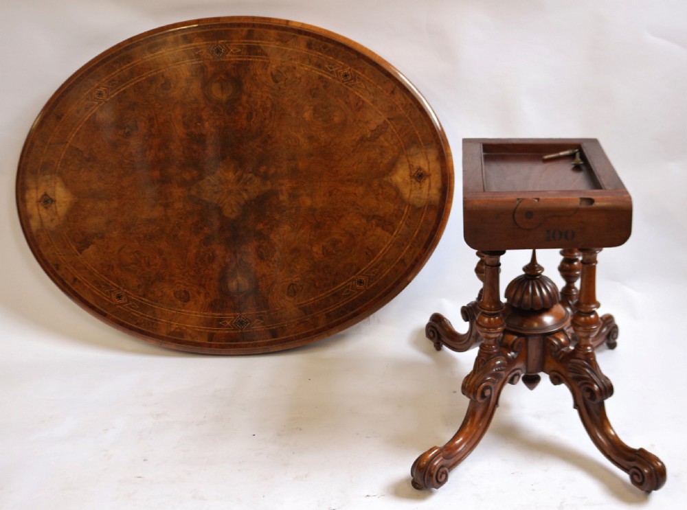 An antique Victorian oval tilt-top loo table crafted from figured walnut with marquetry inlay and carved pedestal legs. View VII