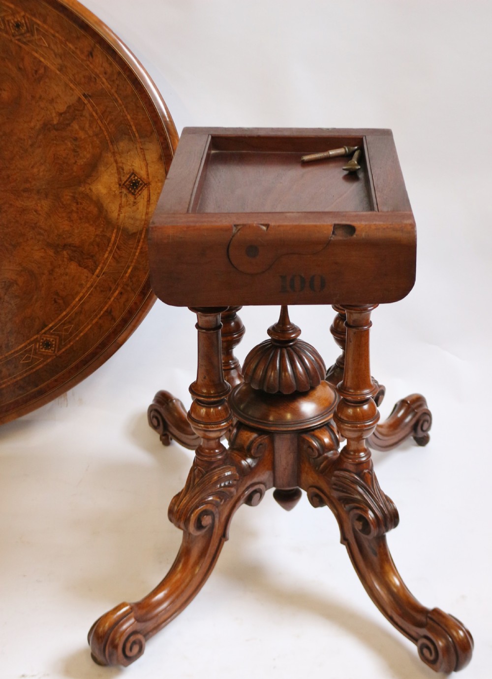 An antique Victorian oval tilt-top loo table crafted from figured walnut with marquetry inlay and carved pedestal legs. View VIII