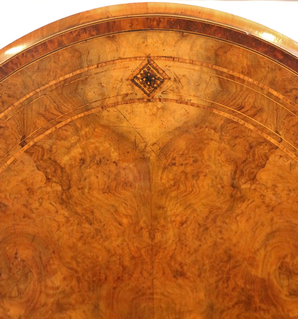 An antique Victorian oval tilt-top loo table crafted from figured walnut with marquetry inlay and carved pedestal legs. View IX