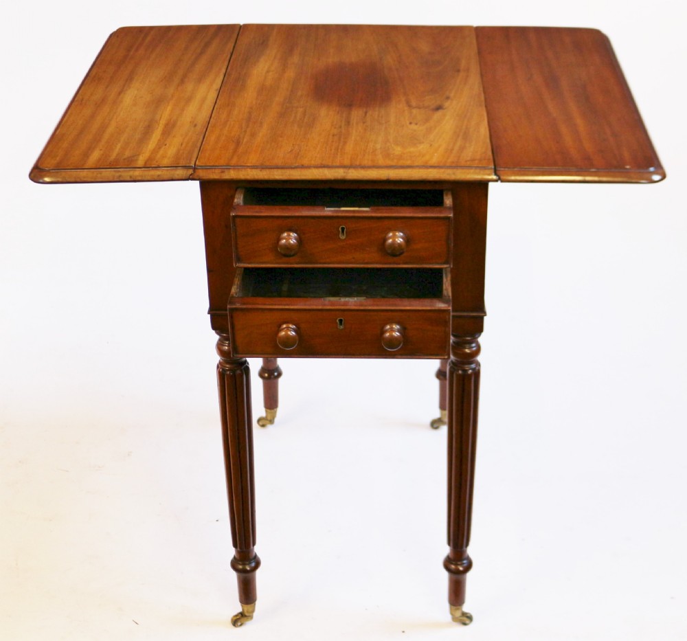 A William IV mahogany drop-leaf table featuring two drawers with wooden knobs, reeded legs, and brass castors. View II