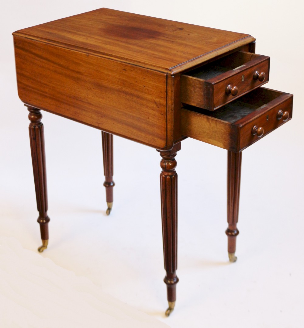 A William IV mahogany drop-leaf table featuring two drawers with wooden knobs, reeded legs, and brass castors. View III