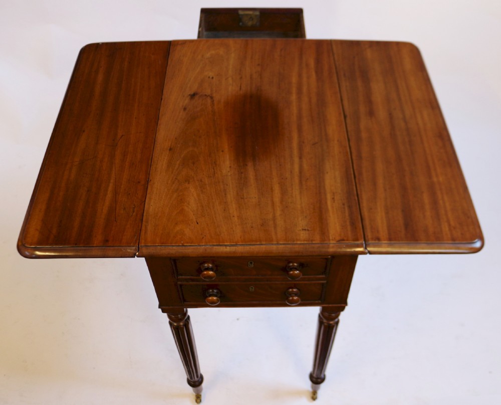 A William IV mahogany drop-leaf table featuring two drawers with wooden knobs, reeded legs, and brass castors. View VI