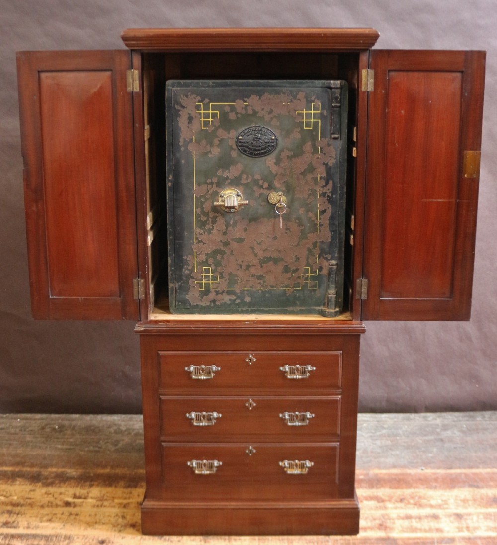 An Edwardian mahogany safe cabinet featuring twin upper panelled doors over three drawers with brass drop handles on a plinth base. View II