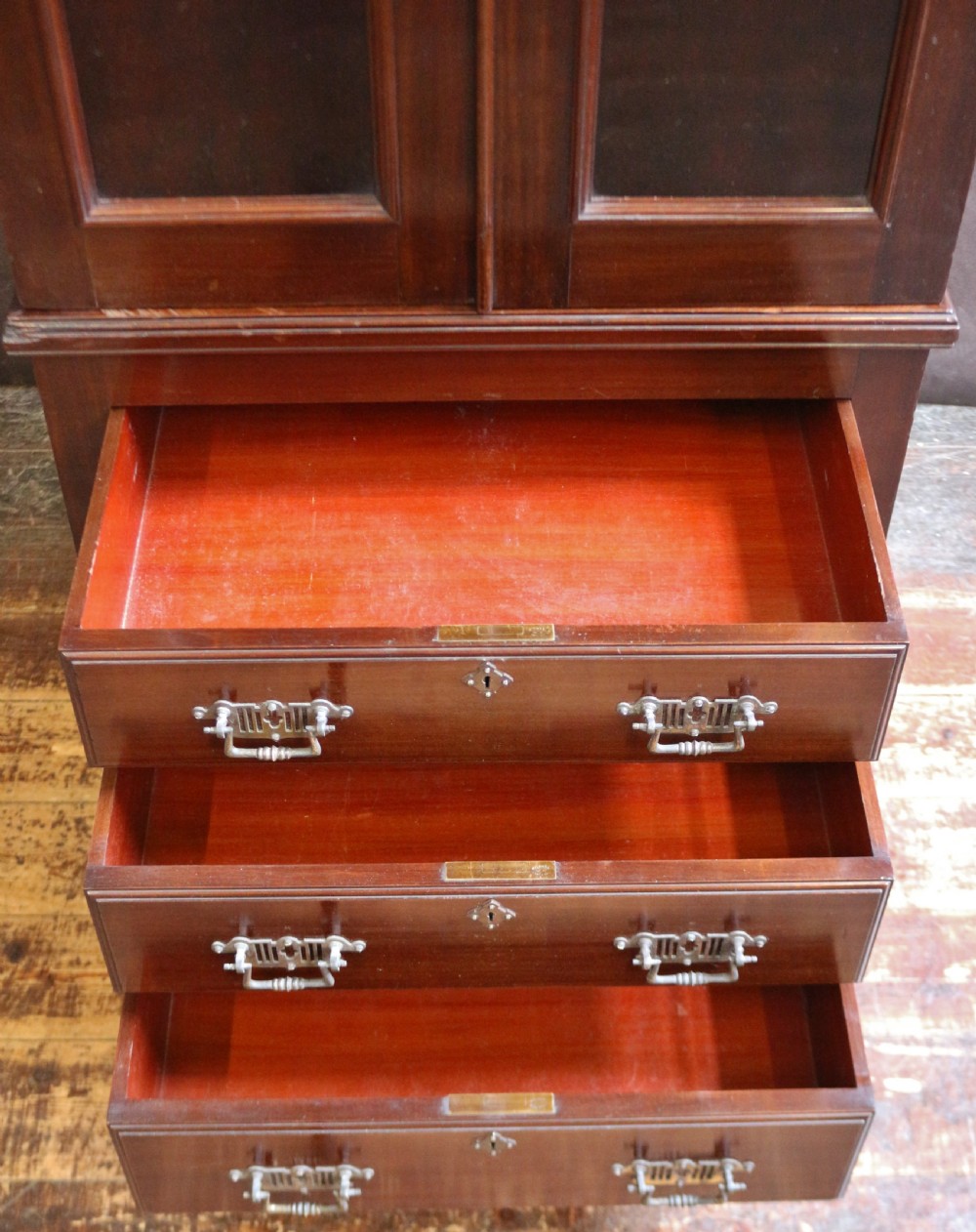 An Edwardian mahogany safe cabinet featuring twin upper panelled doors over three drawers with brass drop handles on a plinth base. View V