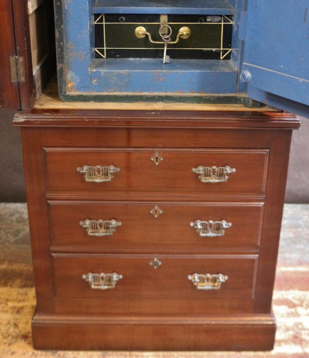An Edwardian mahogany safe cabinet featuring twin upper panelled doors over three drawers with brass drop handles on a plinth base. View XIV