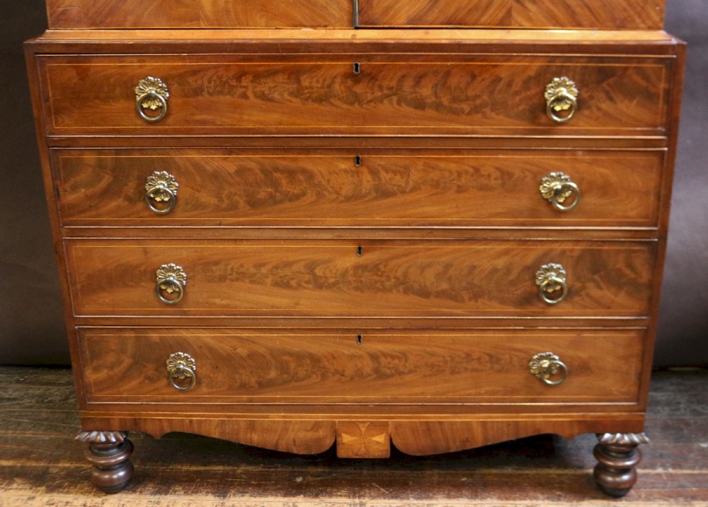 A George III mahogany linen press featuring oval flame mahogany veneered door panels above four drawers with brass handles. View V