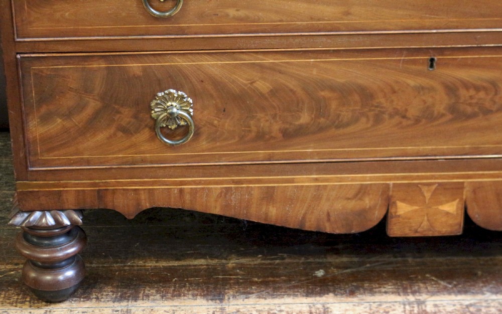 A George III mahogany linen press featuring oval flame mahogany veneered door panels above four drawers with brass handles. View IX