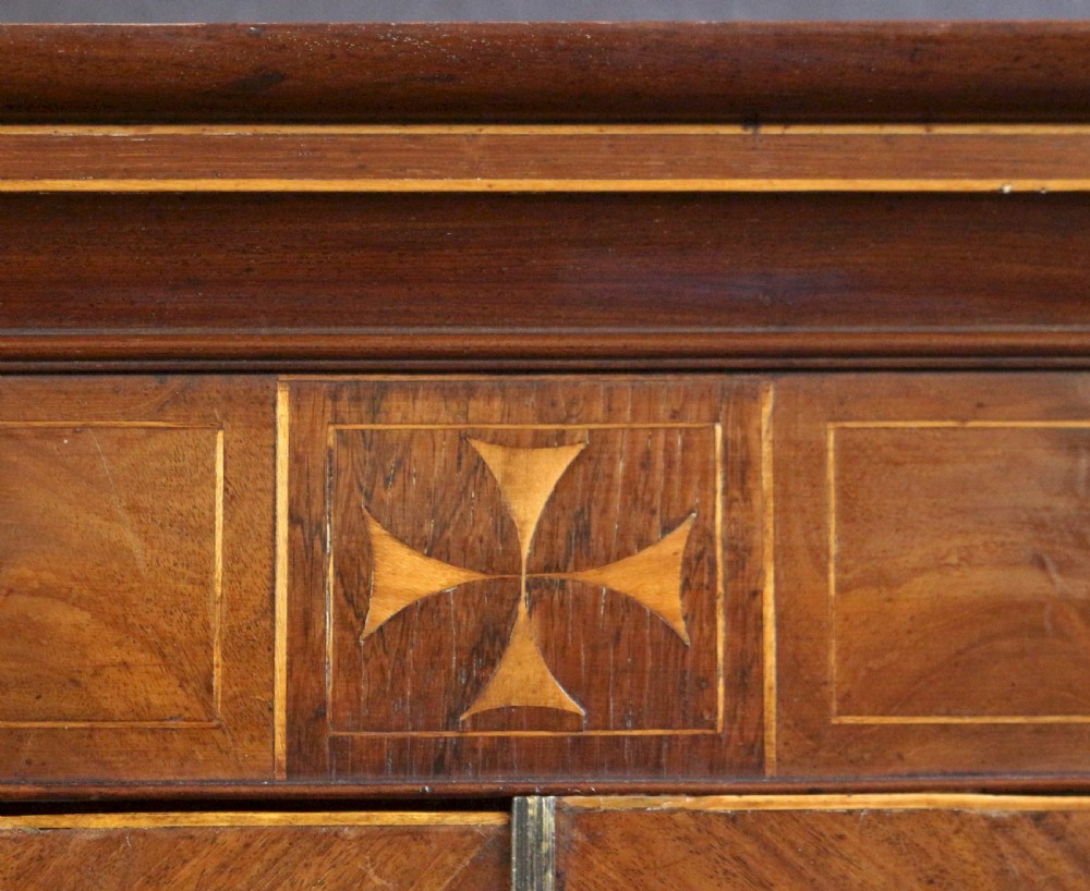 A George III mahogany linen press featuring oval flame mahogany veneered door panels above four drawers with brass handles. View X