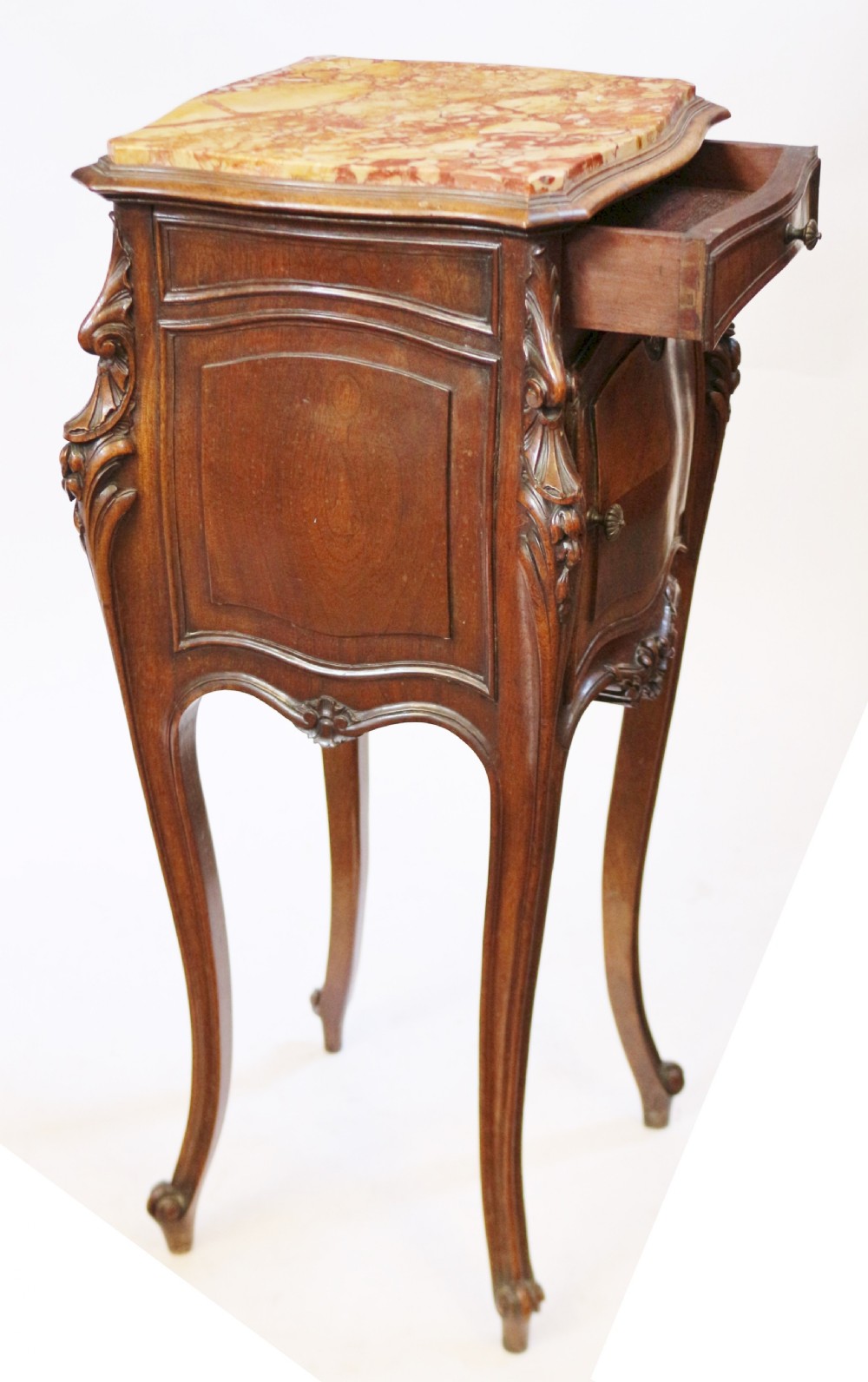 A 19th-century French walnut bedside cupboard featuring an inset variegated marble top, a top drawer, a quarter-veneered cupboard door, ornate rocaille carvings, and slender cabriole legs. View IV
