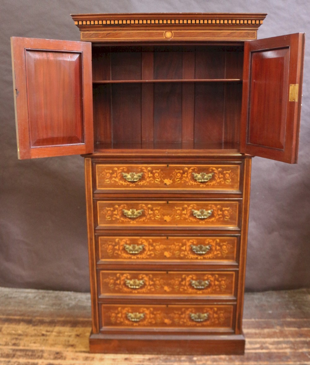 An Edwardian rosewood cupboard on chest featuring elaborate floral satinwood marquetry inlay, a two-door upper section, and five lower drawers with brass handles. View II