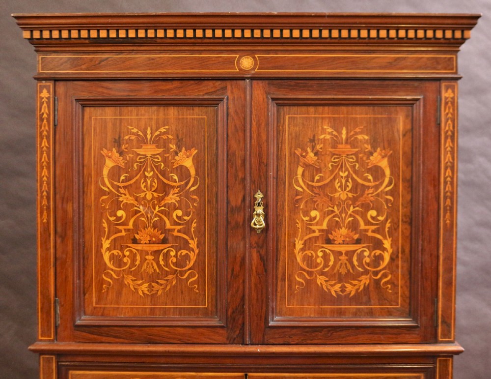 An Edwardian rosewood cupboard on chest featuring elaborate floral satinwood marquetry inlay, a two-door upper section, and five lower drawers with brass handles. View V