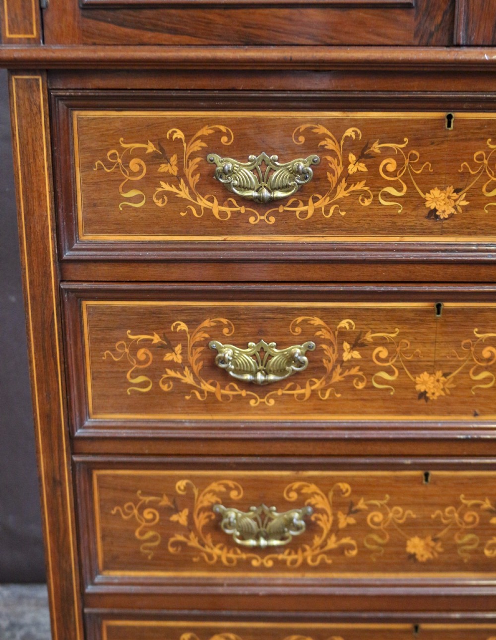 An Edwardian rosewood cupboard on chest featuring elaborate floral satinwood marquetry inlay, a two-door upper section, and five lower drawers with brass handles. View VIII