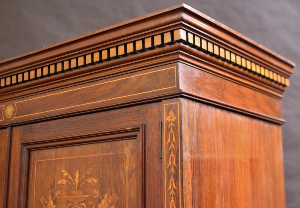 An Edwardian rosewood cupboard on chest featuring elaborate floral satinwood marquetry inlay, a two-door upper section, and five lower drawers with brass handles. View X