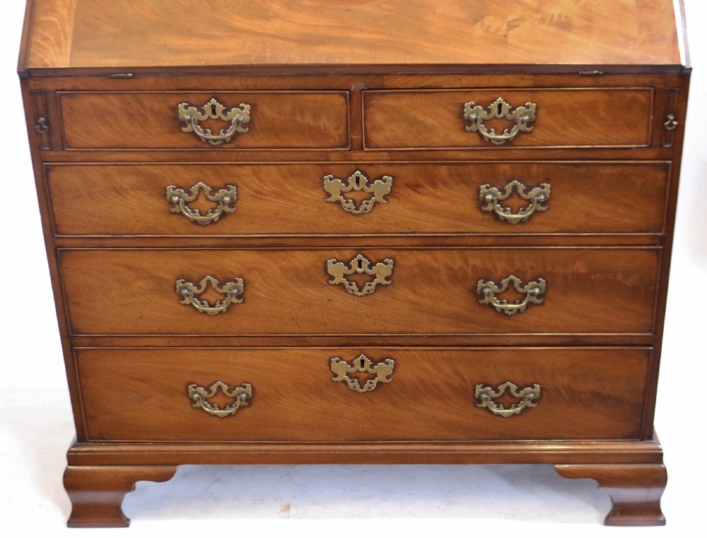 An 18th-century George III mahogany bureau with a slant-front writing slope, five graduated drawers, brass swan-neck handles, and bracket feet. View X