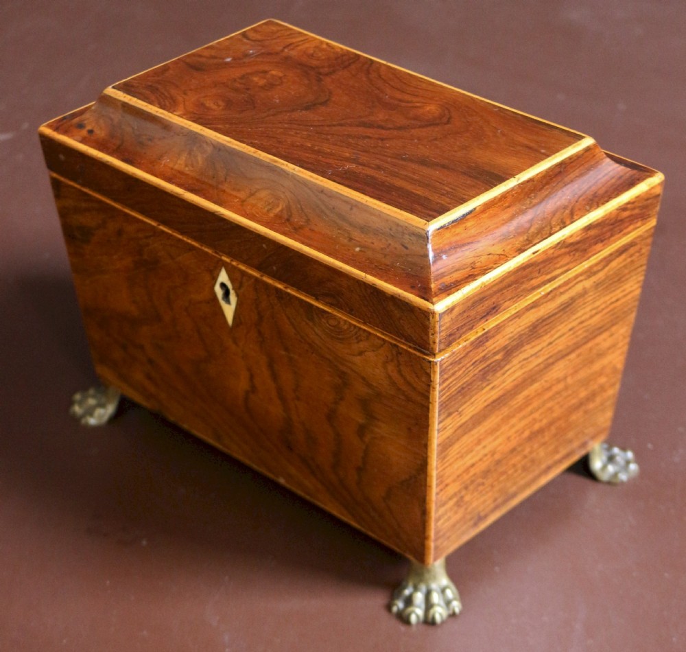 A Regency rosewood tapered oblong tea caddy featuring inlay stringing, a diamond bone escutcheon, and brass lion paw feet. View III
