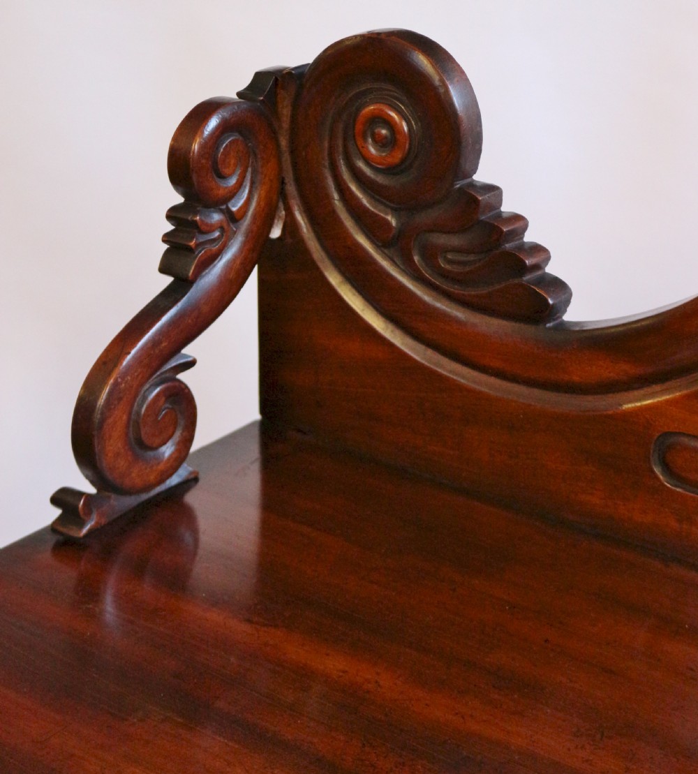 A William IV flame mahogany two-door side cabinet featuring a carved scroll upstand, turned columns, and brass wire mesh panels over pleated lining. View VIII