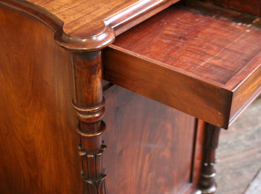 A William IV flame mahogany single-door bedside cupboard featuring a top drawer, carved acanthus leaf side columns, and a plinth base. View IV