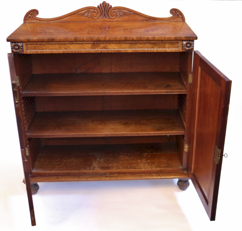 A William IV mahogany two-door side cupboard featuring flame mahogany door panels, a carved scroll backboard, and turned carved feet. View II