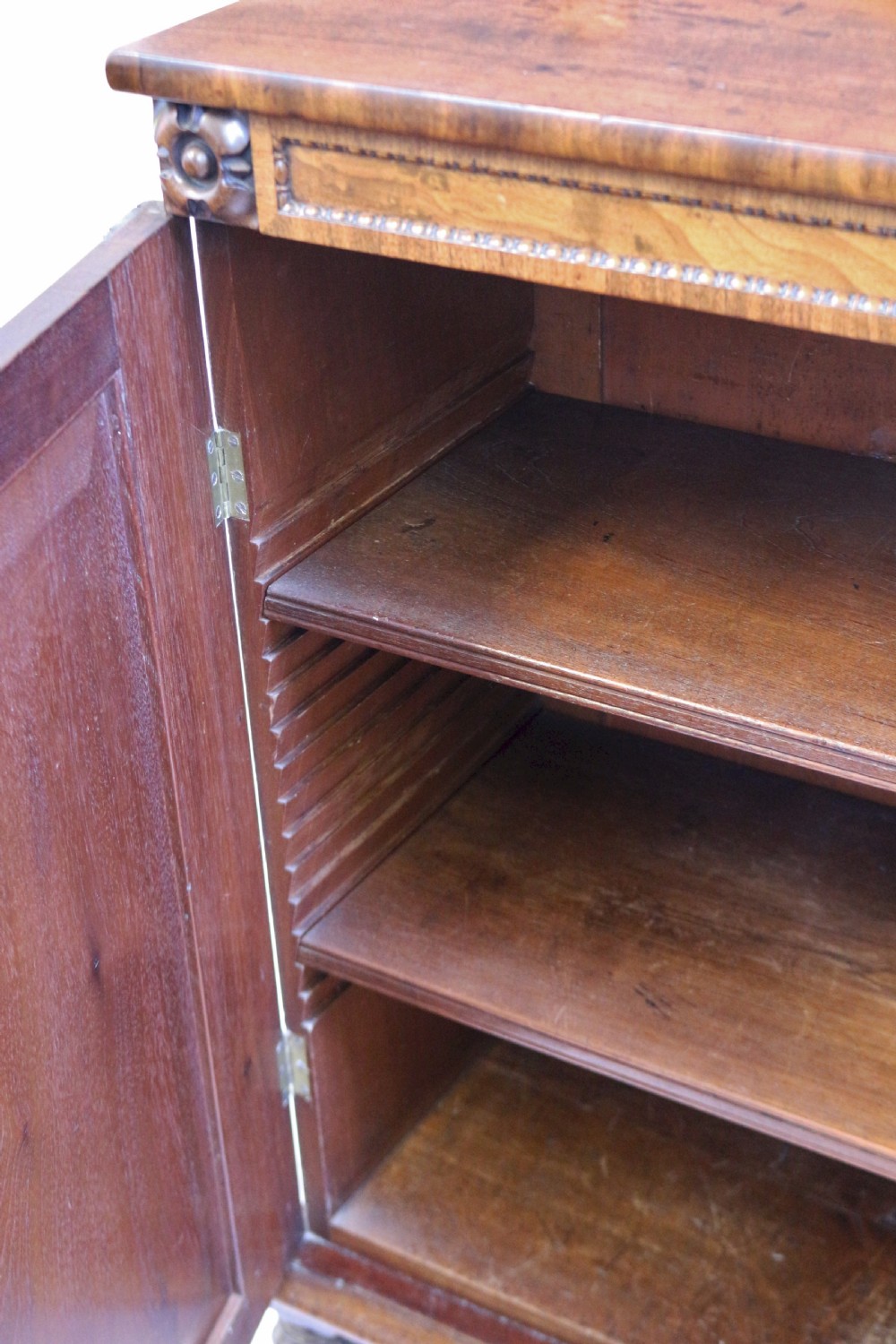 A William IV mahogany two-door side cupboard featuring flame mahogany door panels, a carved scroll backboard, and turned carved feet. View VII