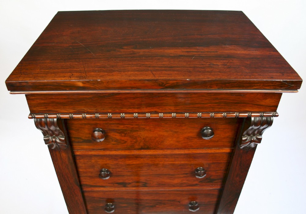 An early Victorian rosewood Wellington chest featuring six graduated drawers with double turned knobs, carved side corbels, and a right-hand side locking pilaster. View IV