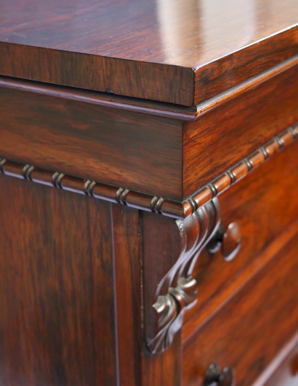 An early Victorian rosewood Wellington chest featuring six graduated drawers with double turned knobs, carved side corbels, and a right-hand side locking pilaster. View V