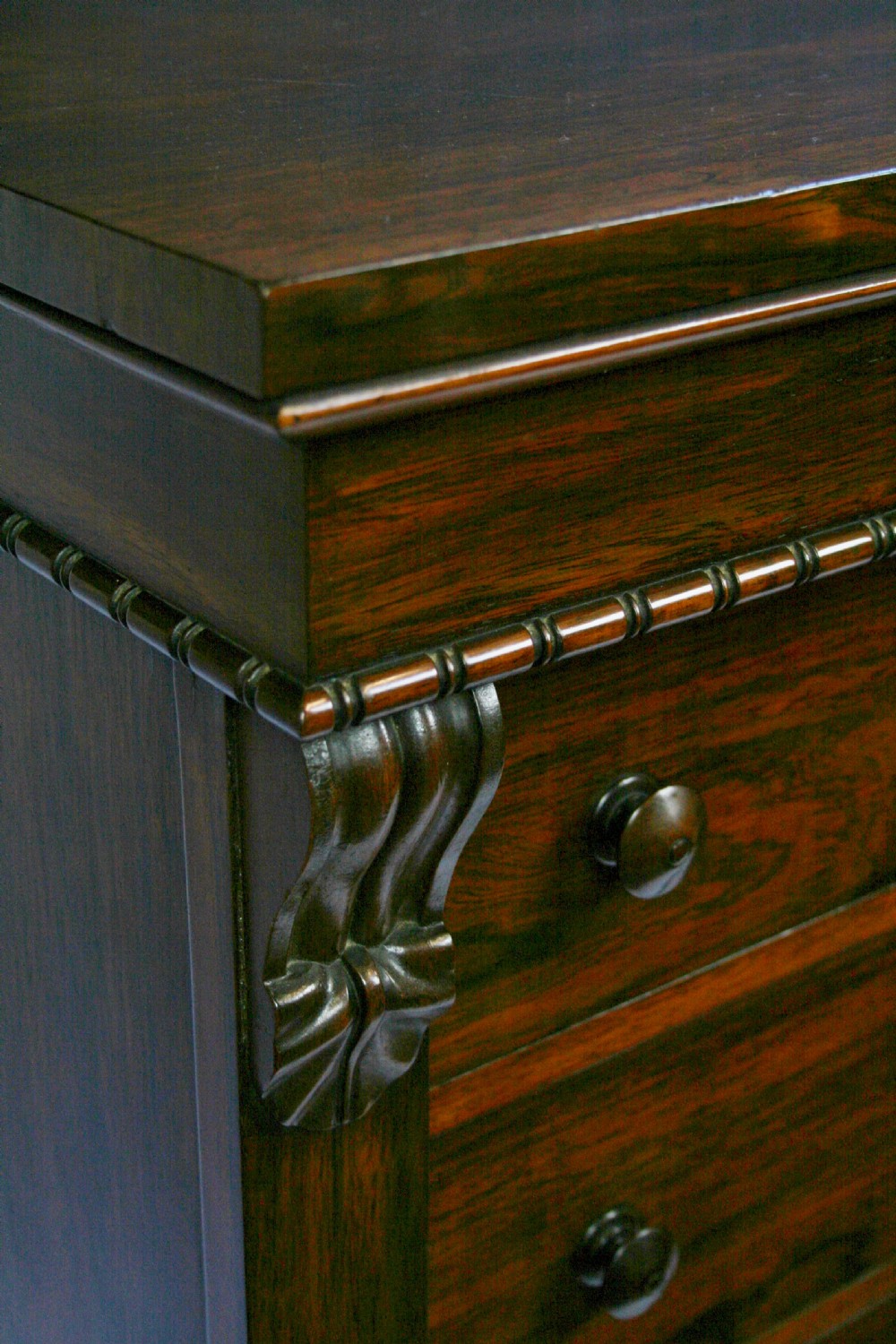 An early Victorian rosewood Wellington chest featuring six graduated drawers with double turned knobs, carved side corbels, and a right-hand side locking pilaster. View VI