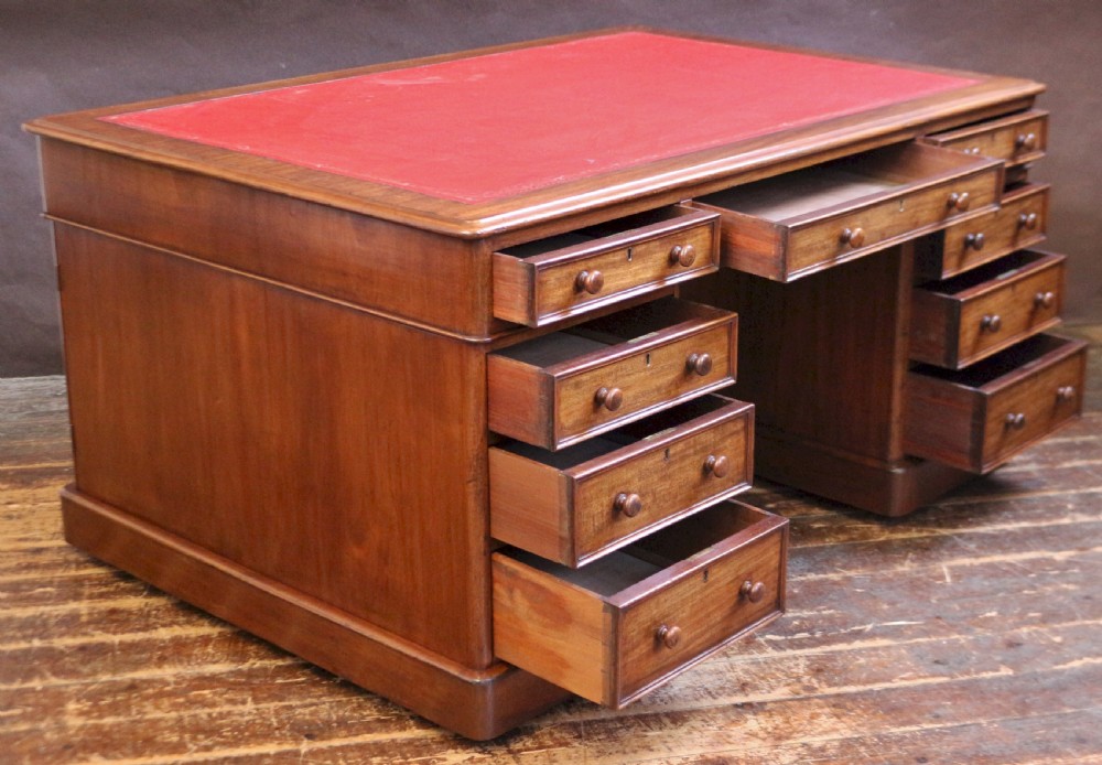A Victorian mahogany three-part partners desk featuring a red leather writing inset and multiple drawers on two pedestals with turned wooden knobs. View II
