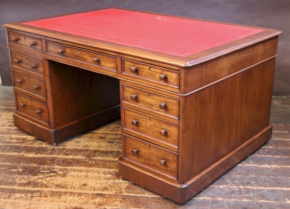 A Victorian mahogany three-part partners desk featuring a red leather writing inset and multiple drawers on two pedestals with turned wooden knobs. View III