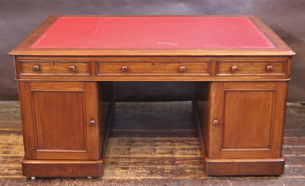 A Victorian mahogany three-part partners desk featuring a red leather writing inset and multiple drawers on two pedestals with turned wooden knobs. View IV