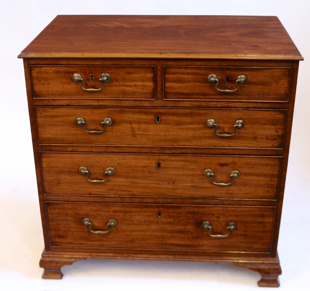 An antique Georgian mahogany chest of drawers featuring a two-over-three drawer configuration with brass swan-neck handles and shaped ogee bracket feet.