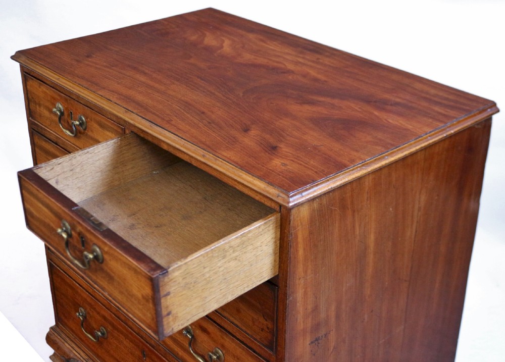 An antique Georgian mahogany chest of drawers featuring a two-over-three drawer configuration with brass swan-neck handles and shaped ogee bracket feet. View V