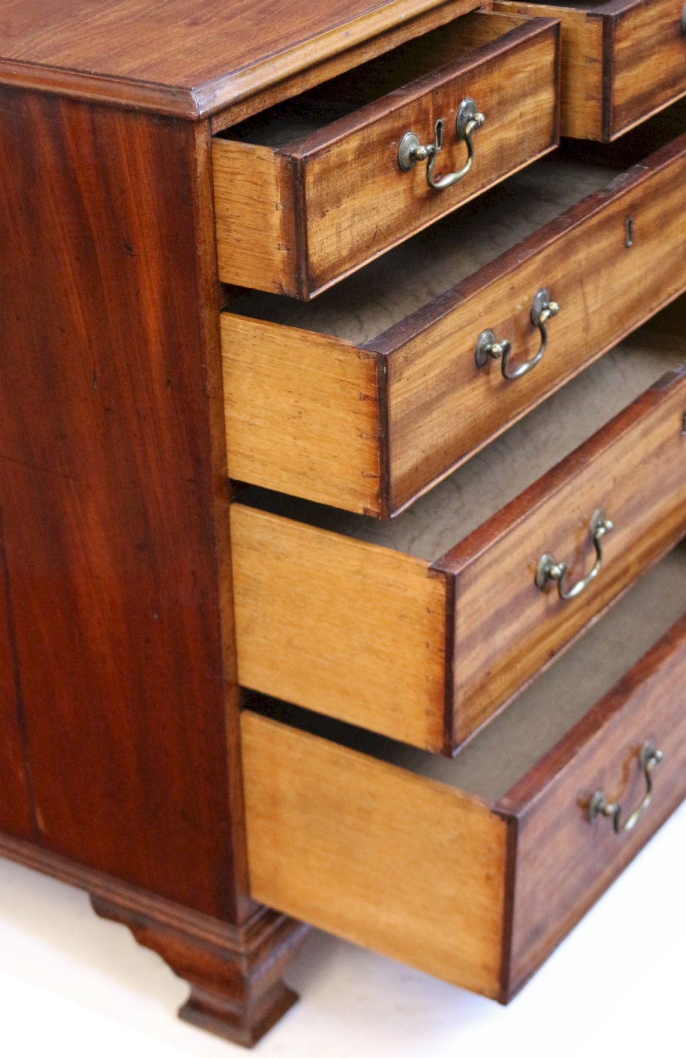 An antique Georgian mahogany chest of drawers featuring a two-over-three drawer configuration with brass swan-neck handles and shaped ogee bracket feet. View VI