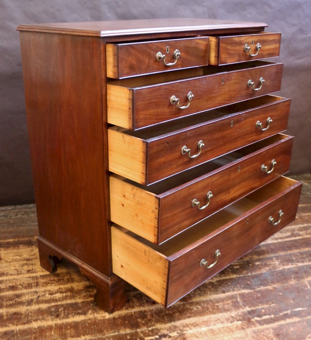 A Georgian mahogany chest of six drawers arranged in a two short over four long graduated design with brass swan-neck handles and bracket feet. View II