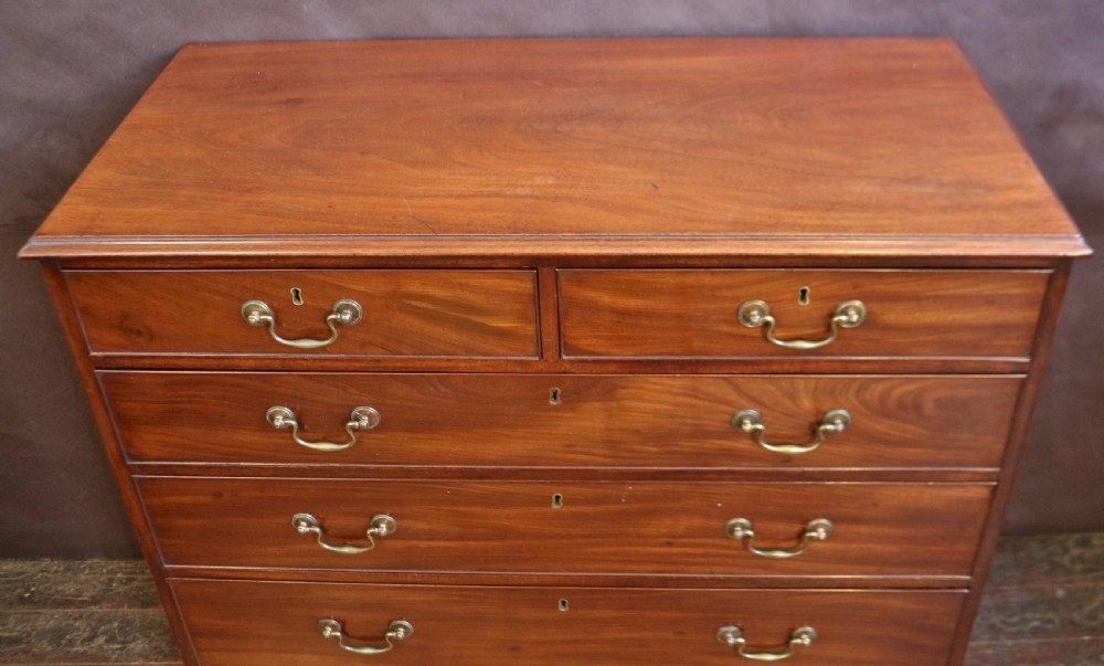 A Georgian mahogany chest of six drawers arranged in a two short over four long graduated design with brass swan-neck handles and bracket feet. View V