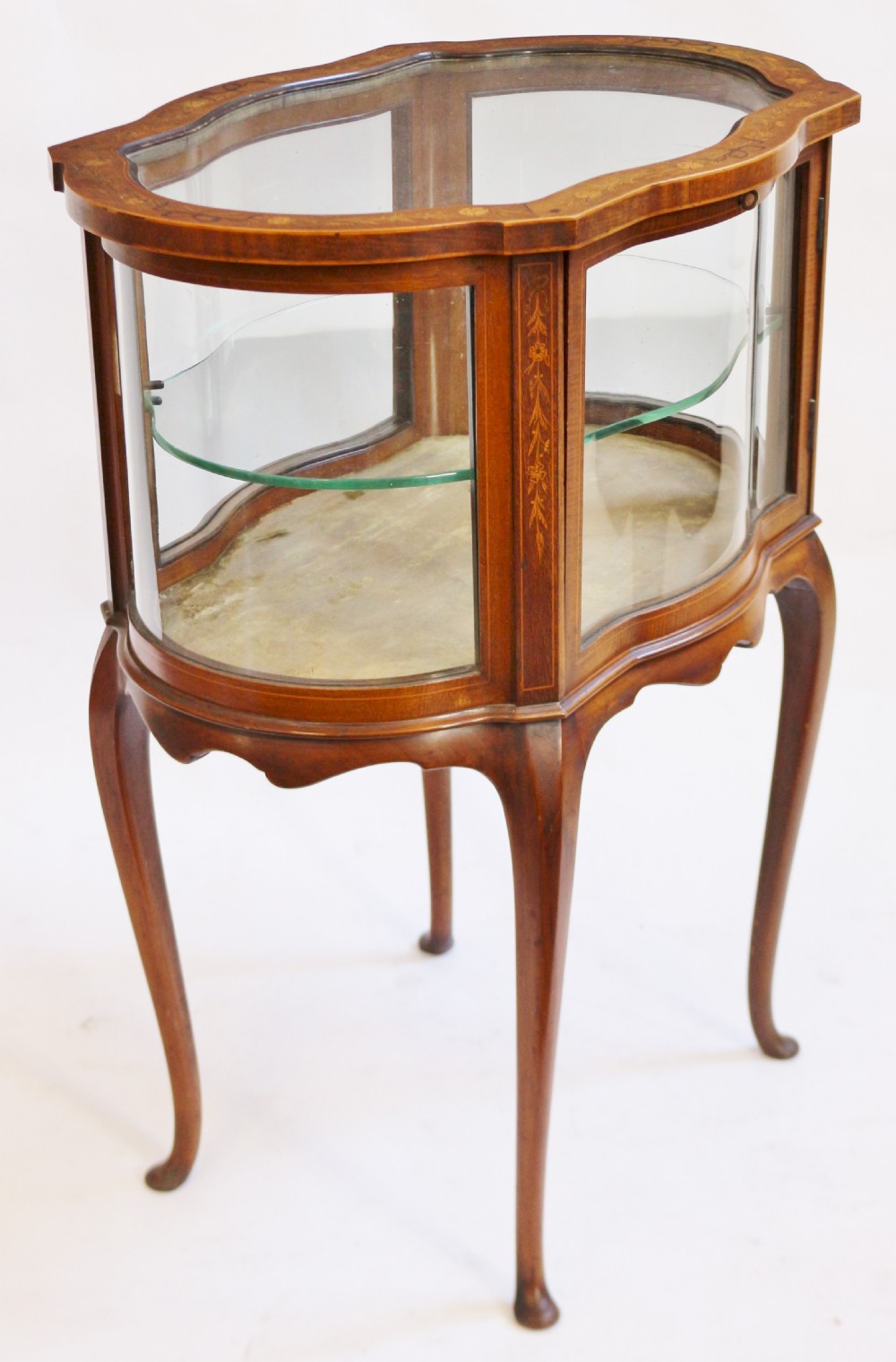 An Edwardian serpentine-shaped mahogany bijouterie cabinet featuring glass display panels, satinwood inlay along the top border, and slender cabriole legs. View III