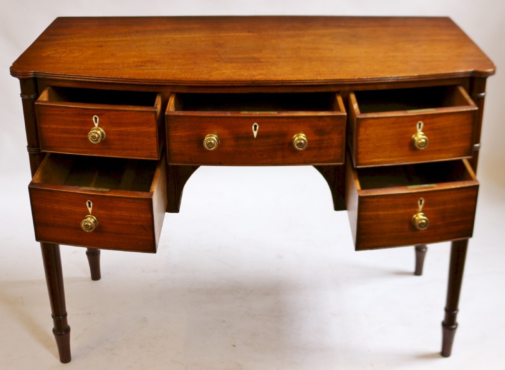 A George IV mahogany bowfront kneehole table with five drawers, brass knobs, teardrop escutcheons, and turned legs. View II