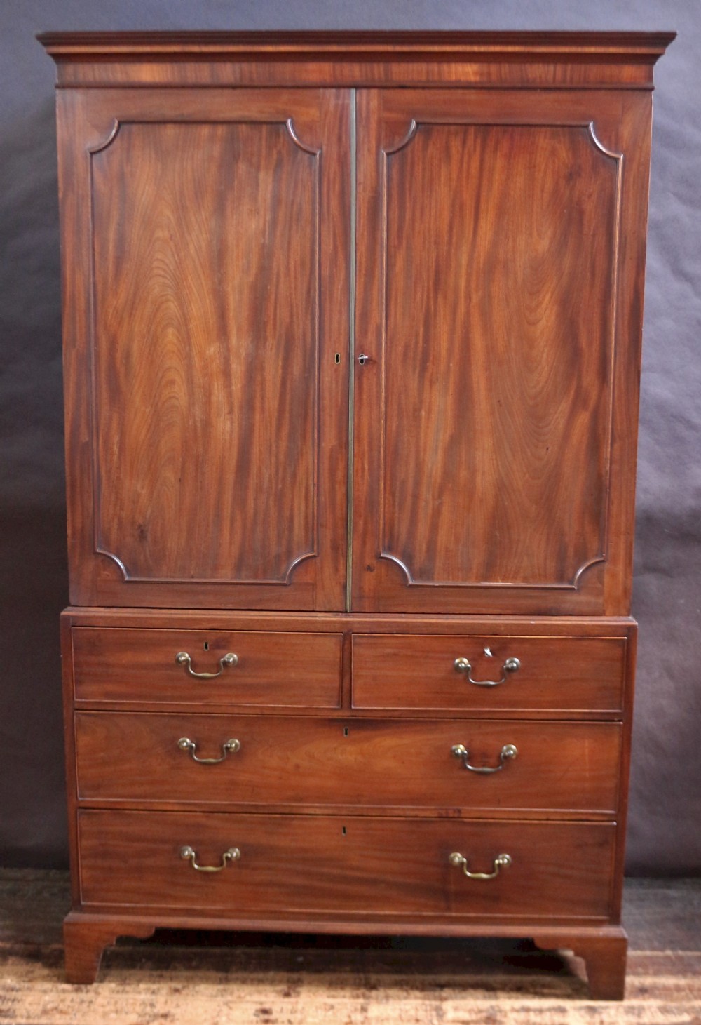 A Georgian mahogany linen press featuring panelled double doors above a chest with two short and two long drawers raised on bracket feet.